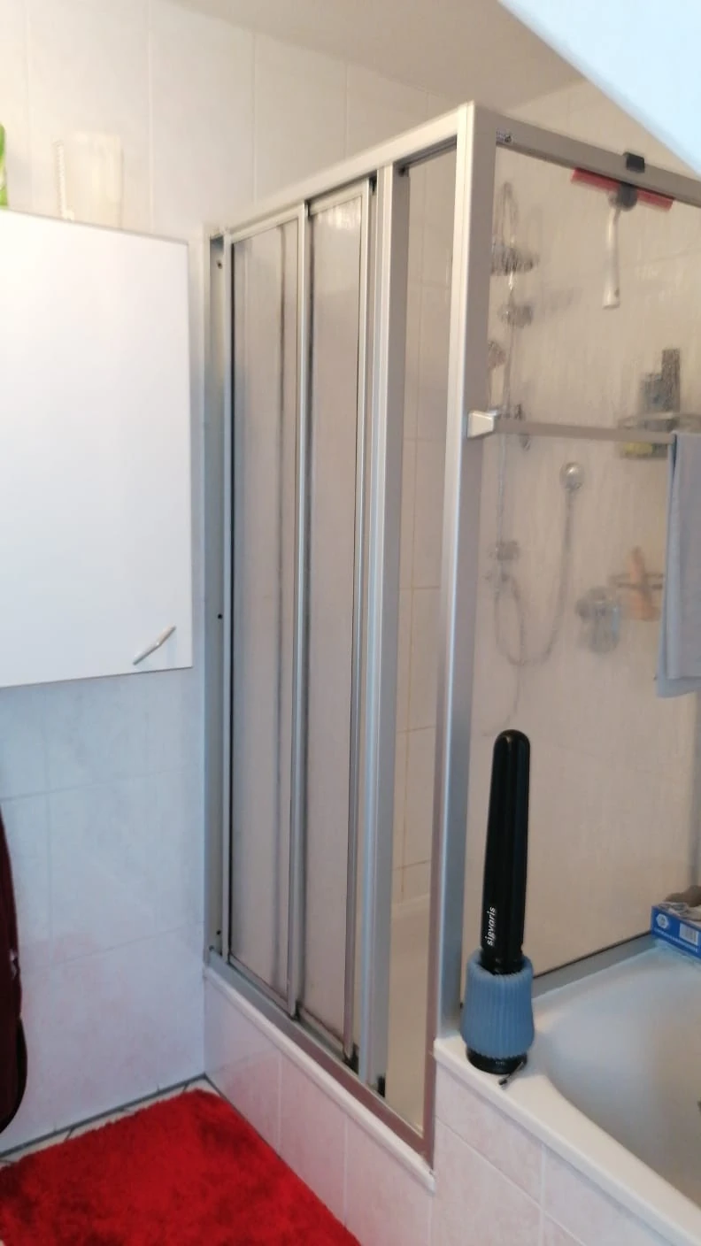 Alte Duschfaltwand über der Badewanne mit vergilbten Scheiben