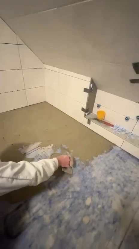 Handwerker zieht die Abdichtung auf dem Boden des Duschbereichs ab
