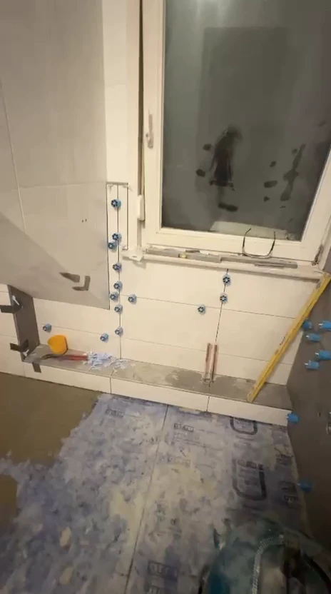 Fliesenarbeiten mit Nivelliersystem an der Wand im Badezimmer