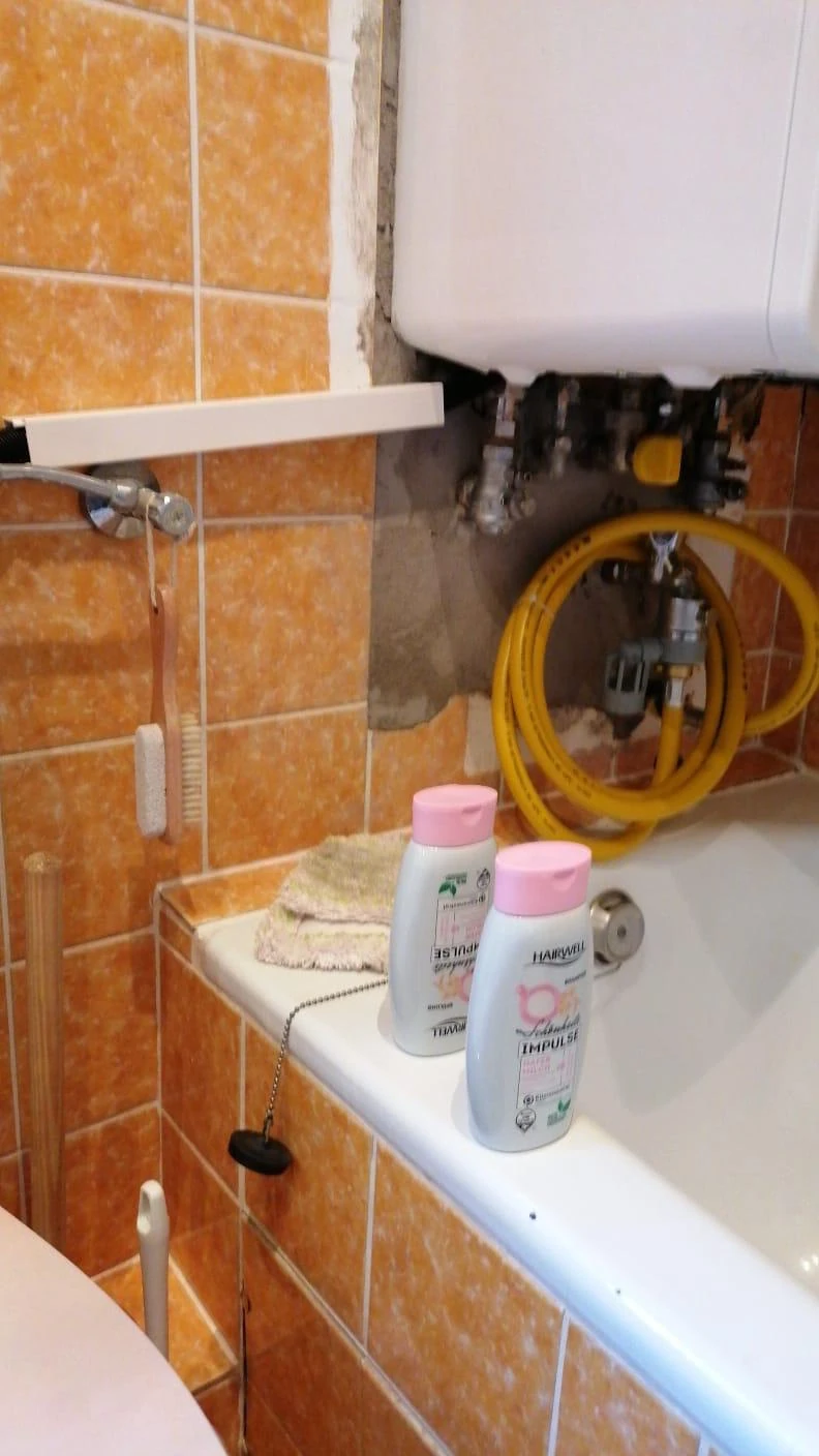 Freiliegende Leitungen unter der alten Therme mit Feuchtefleck an der Wand