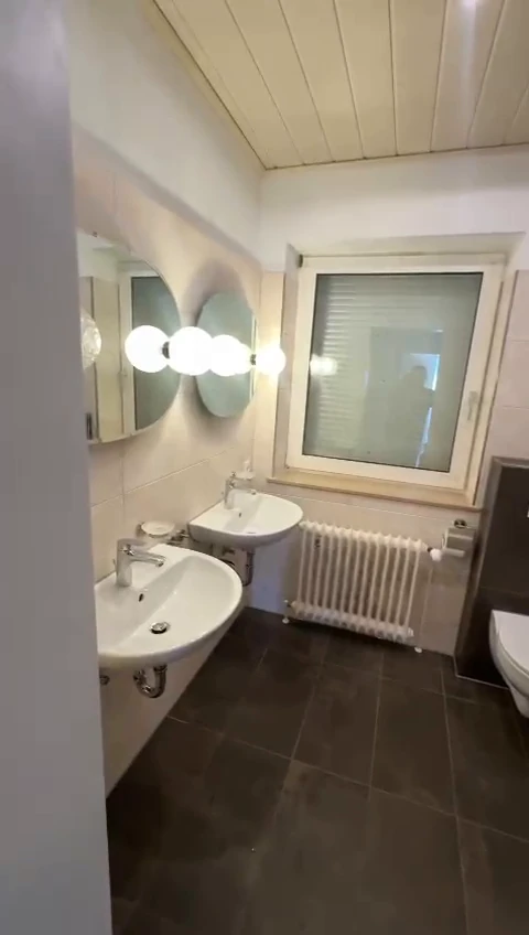 Saniertes Altbau-Bad mit zwei Waschbecken und runden Spiegeln