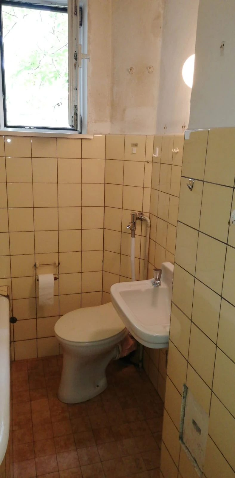Enges Bad mit gelben Fliesen, Stand-WC und Eckwaschbecken